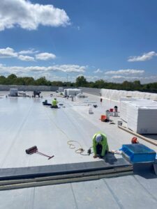 Commercial roofing crew installing single-ply roofing system on building