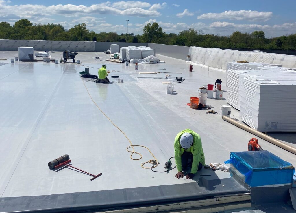 Commercial roofing crew installing single-ply roofing system on building
